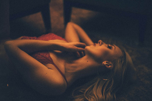 Une belle jeune femme blonde qui porte un soutien-gorge rouge et allongée sur le sol dans une lumière tamisée | Watsunder